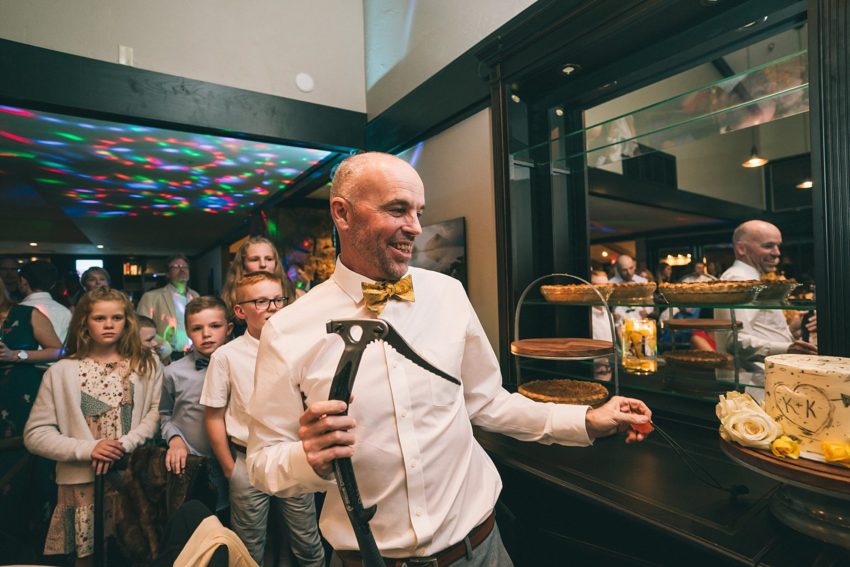 Groom cuts wedding cake with an ice axe