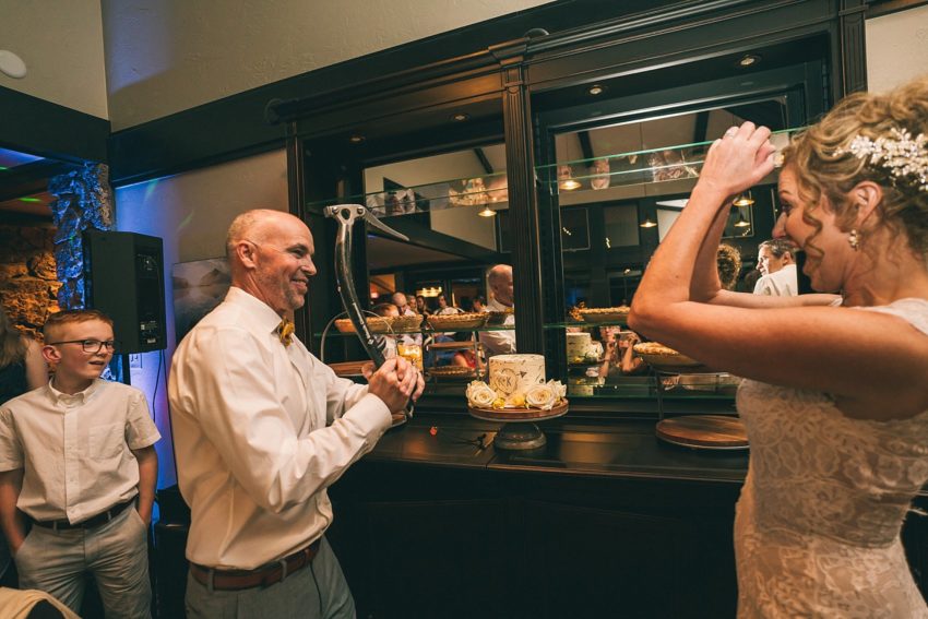 Groom cuts wedding cake with an ice axe