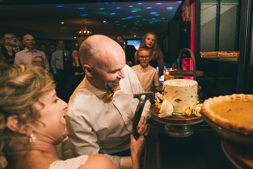bride and Groom cuts wedding cake with an ice axe