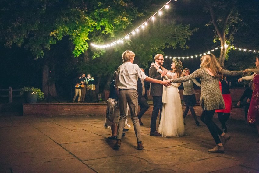 Bride and groom surrounded by wedding guests during wedding reception dancing